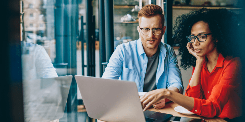 Image of a man and woman sitting beside each other in front of a laptop going through their firm's audit and assurance processes.