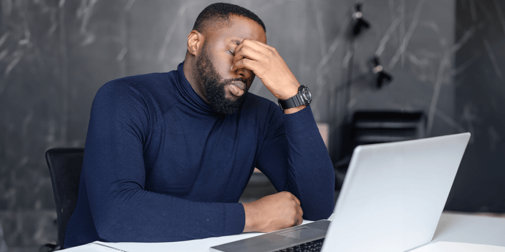 Man holds his face in his hands, frustrated that he has become yet another ransomware victim.