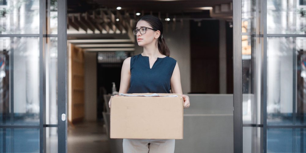 Woman quitting her job, holding a cardboard box.