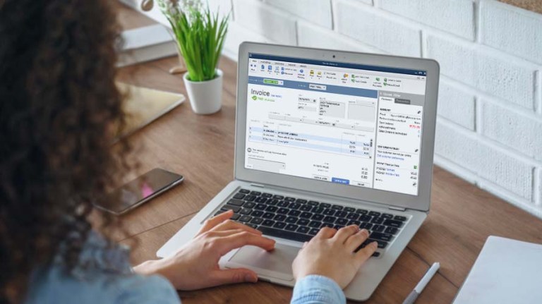 A person working on a laptop with the screen showing them working inside of QuickBooks.