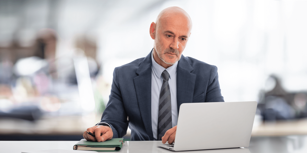 A man with a focused look on his face looks at a laptop as he considers his email security best practices.