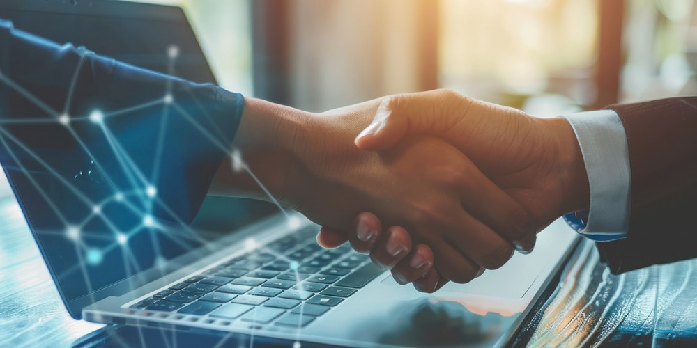 An image of two business people shaking hands in front of a laptop as they agree on client accounting and advisory services