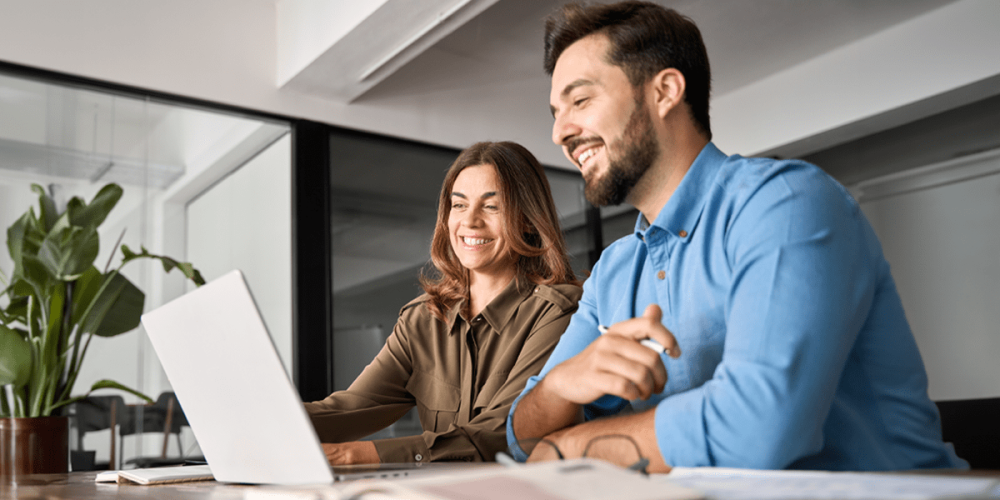 A smiling man and woman sit in front of a laptop, taking a quiz to see if they're running a modern accounting firm.