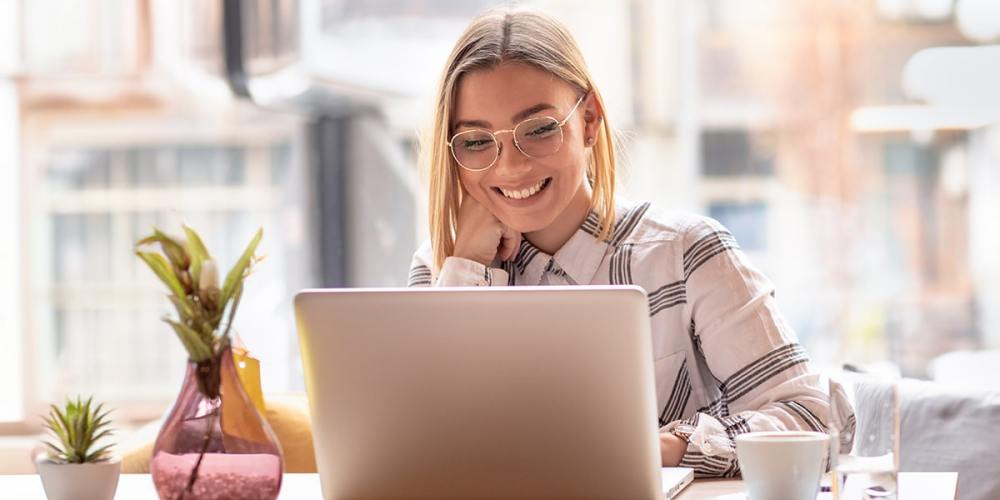 A woman sitting at a laptop smiles because she's achieved efficiency in accounting with Transaction Pro's new features.