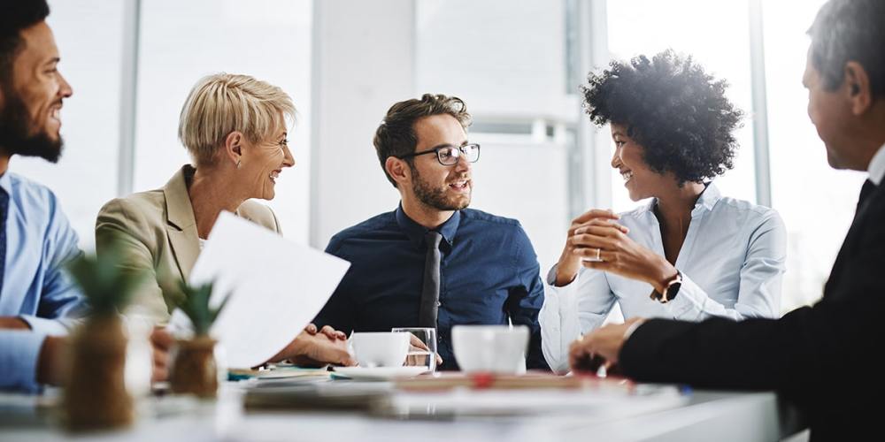 A group of diverse accounting firm employees sit around a table, discussing the Retention Revolution.