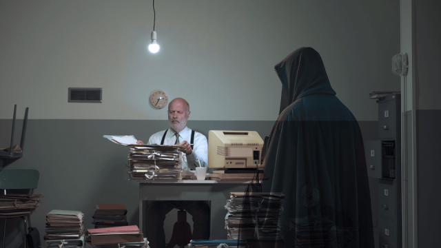 The translucent Ghost of Christmas Past appears in front of Ledger sitting at his desk.