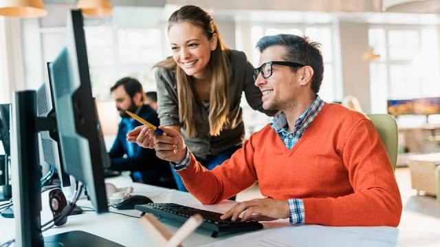 A man and woman point to a computer screen as they explore use cases for AI in their small accounting firm.