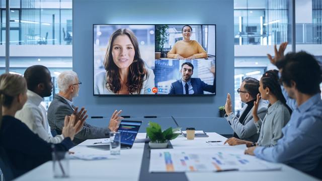 Accounting staff sit around a conference table as they speak with their clients virtually.