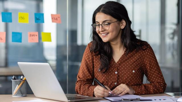 A woman sits at a laptop, working efficiently.